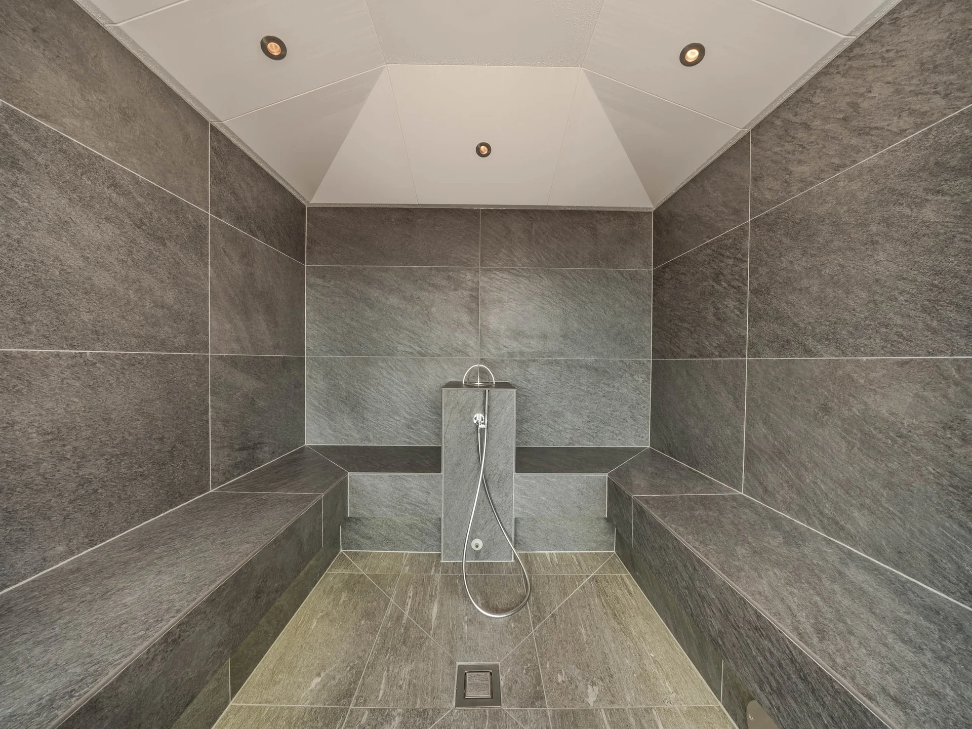Unser Wellnesshotel in Alta Badia: das Nature Hotel Delta Moderner Dampfraum mit grauen Fliesen und Sitzbänken