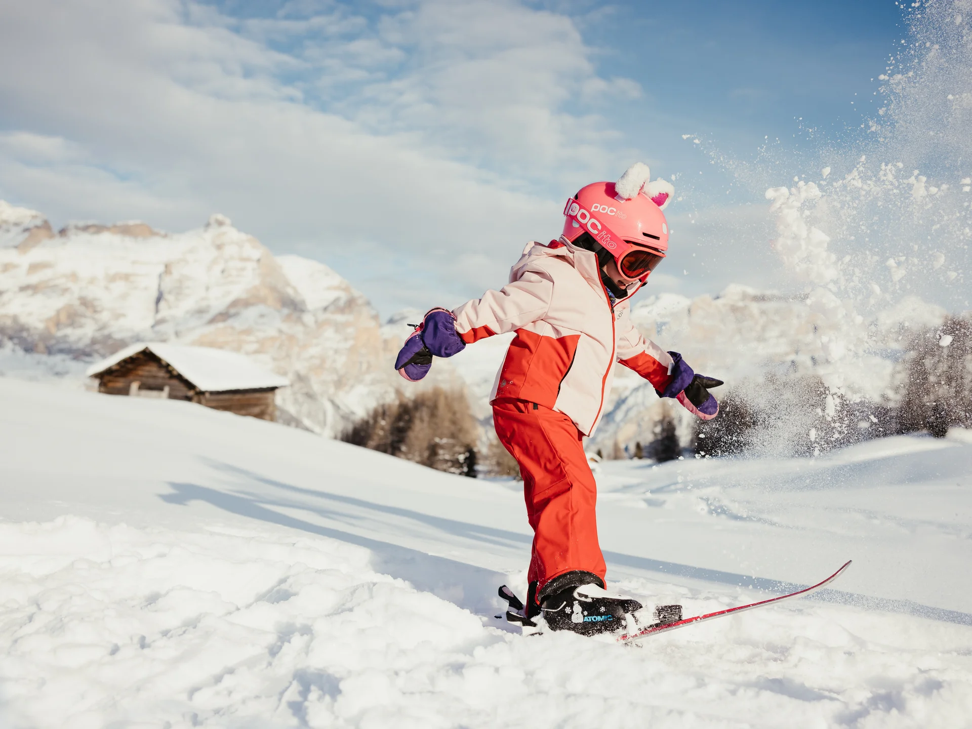 Das ist sehenswert in der Umgebung des Nature Hotel Delta. Kind in roter Skibekleidung fährt im Schnee mit Skiern in den Bergen