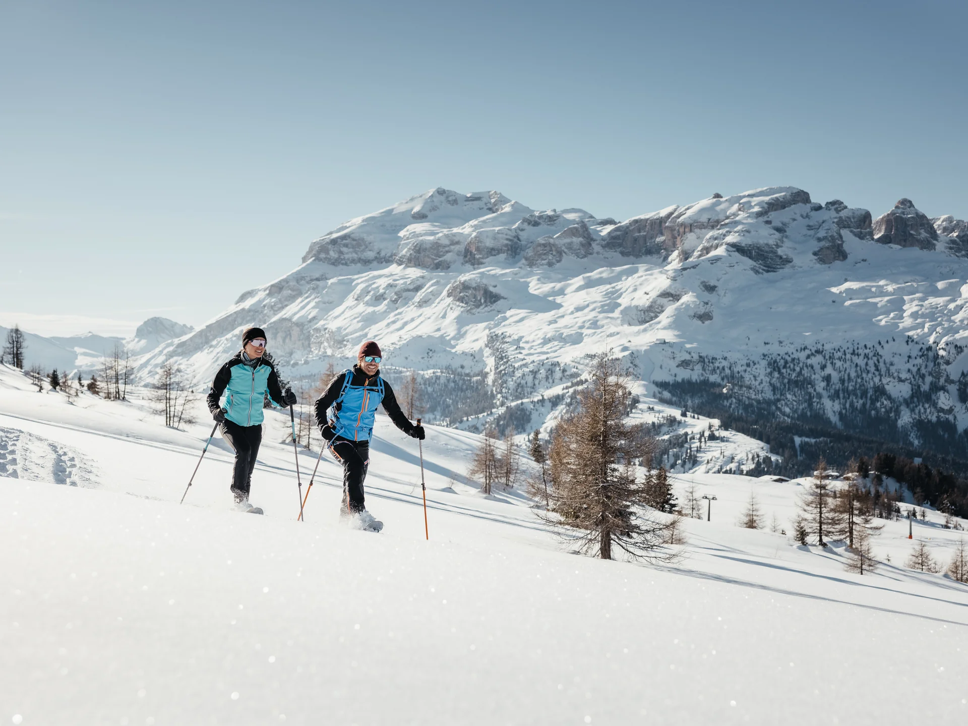 Zwei Personen beim Schneeschuhwandern vor schneebedeckten Bergen