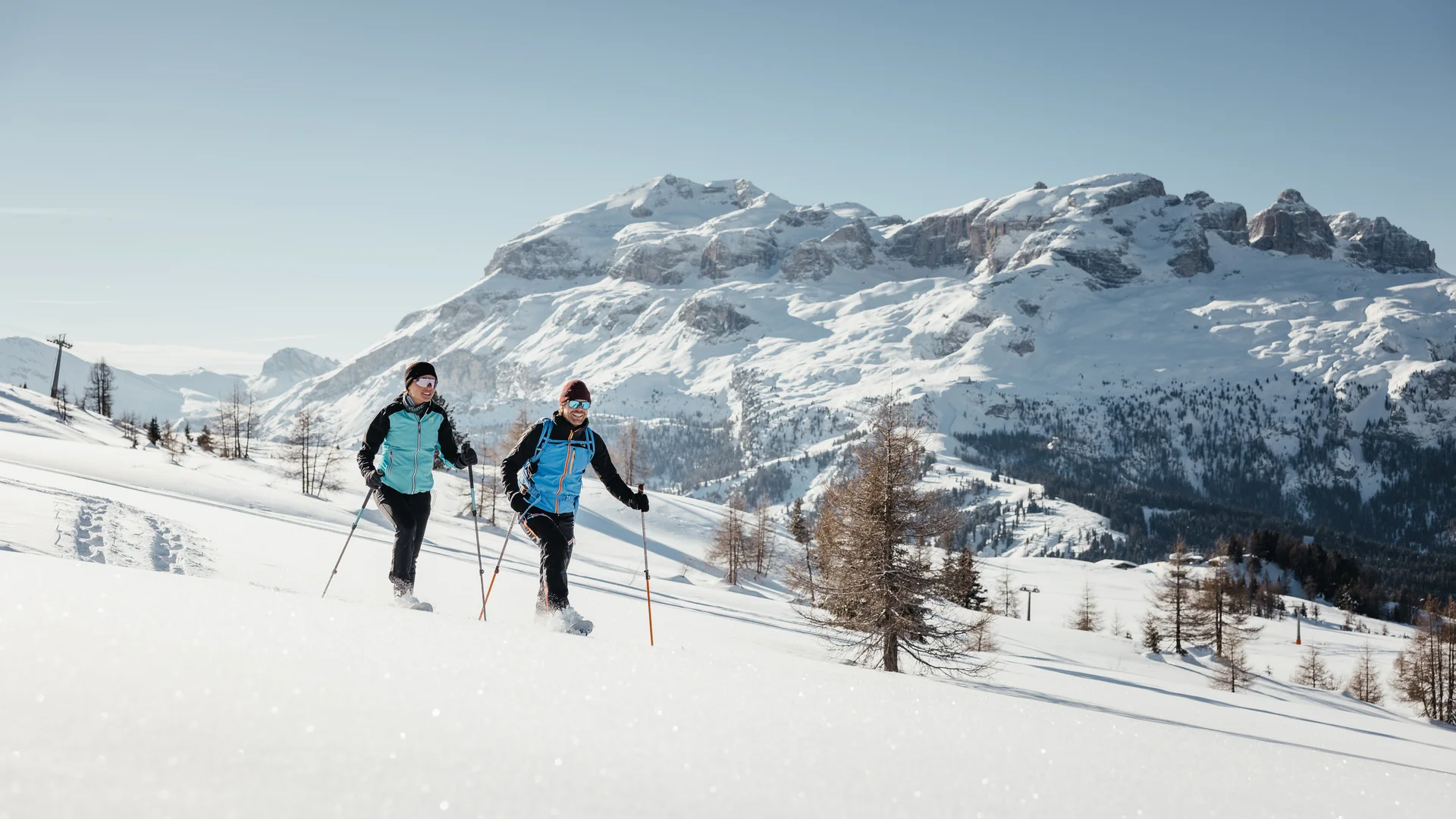Die schönsten Eindrücke aus dem Nature Hotel Delta Zwei Personen beim Schneeschuhwandern vor schneebedeckten Bergen