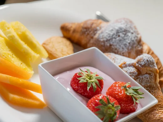 Frühstücksteller mit Croissants, Erdbeeren, Joghurt und frischem Obst