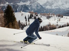 Den Winter in Alta Badia genießen – im Nature Hotel Delta Skifahrer fährt auf verschneiter Piste mit Bergen im Hintergrund