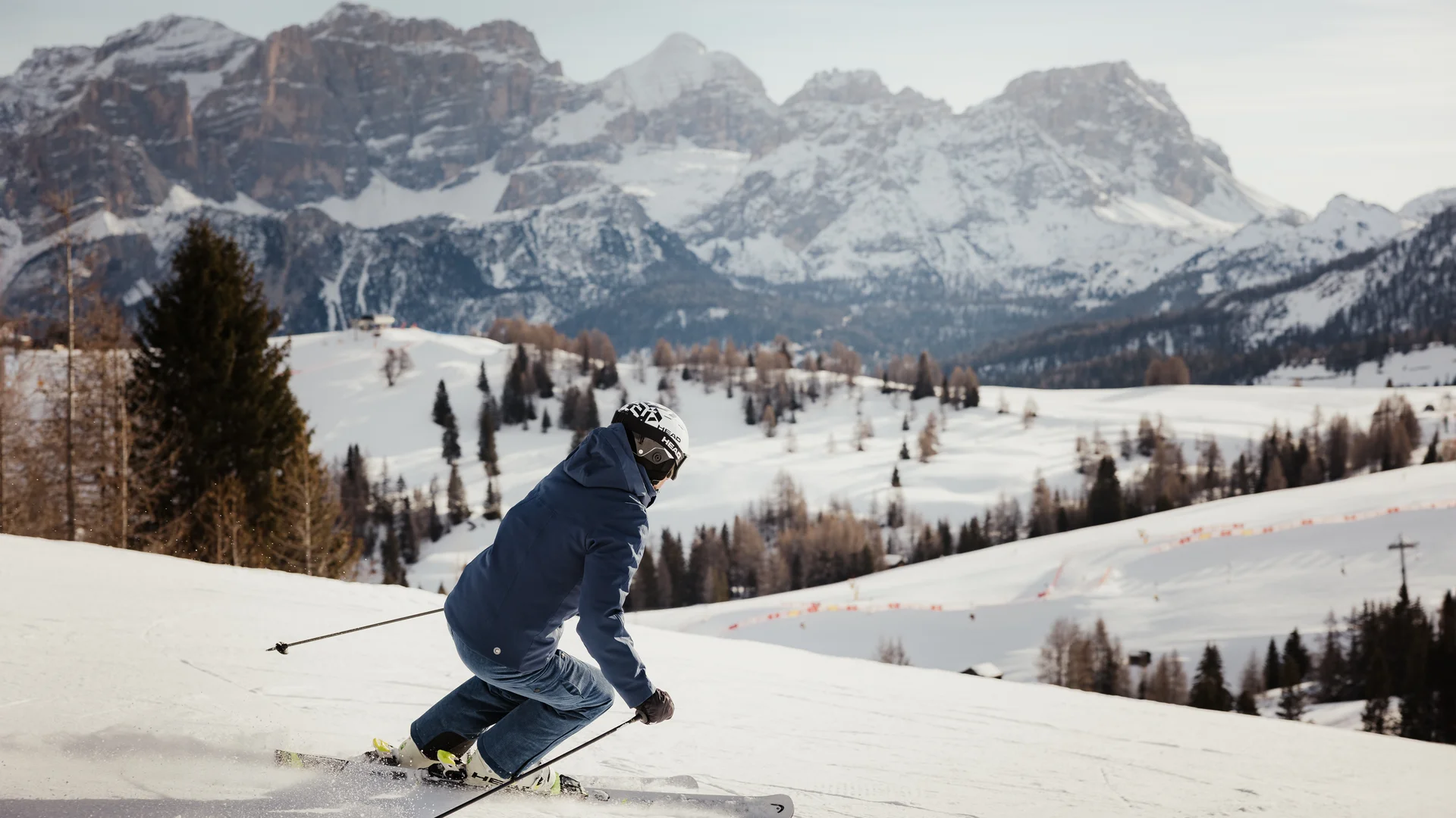 Die schönsten Eindrücke aus dem Nature Hotel Delta Skifahrer fährt auf verschneiter Piste mit Bergen im Hintergrund