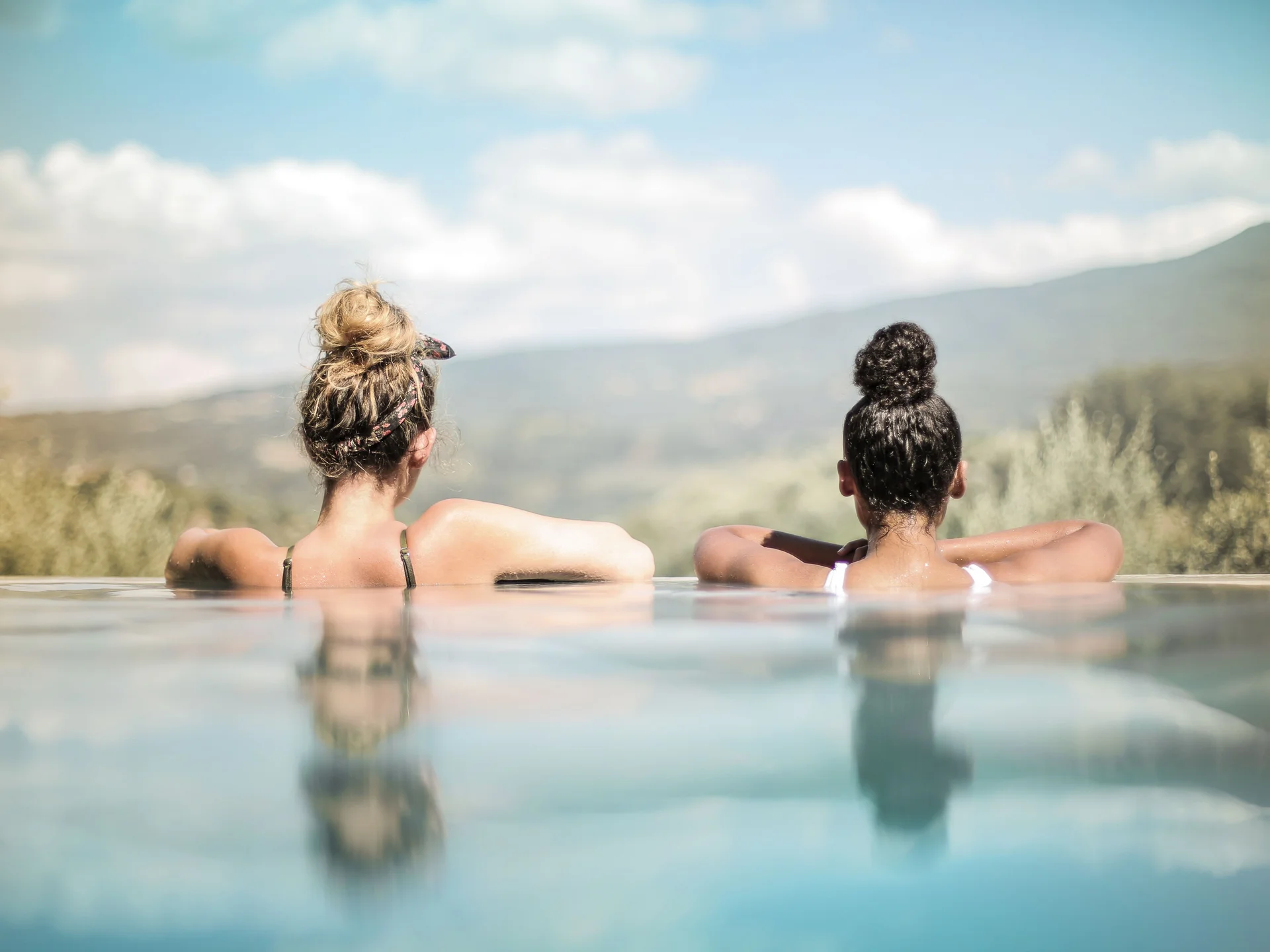 Unser Wellnesshotel in Alta Badia: das Nature Hotel Delta Zwei Frauen entspannen im Pool mit Blick auf die Berge