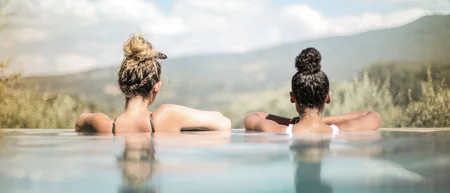 Zwei Frauen entspannen im Pool mit Blick auf die Berge