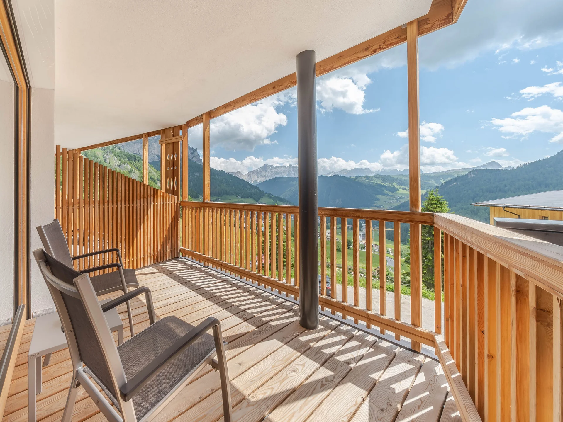 Il vostro hotel con spa in Alta Badia: il Nature Hotel Delta Balcone con due sedie e vista sulle montagne in una giornata di sole