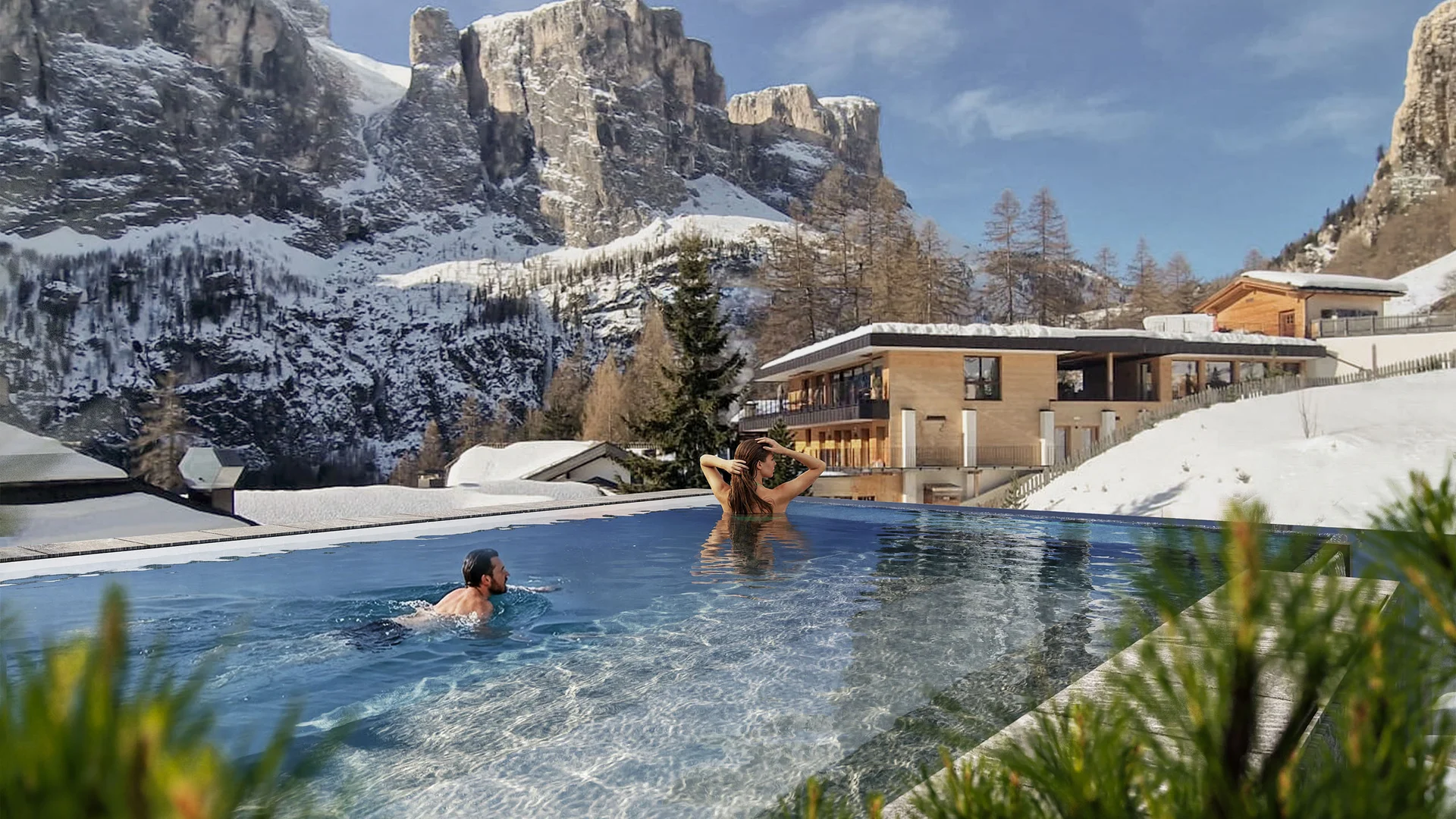 Menschen schwimmen im Außenpool mit Blick auf schneebedeckte Berge und Gebäude