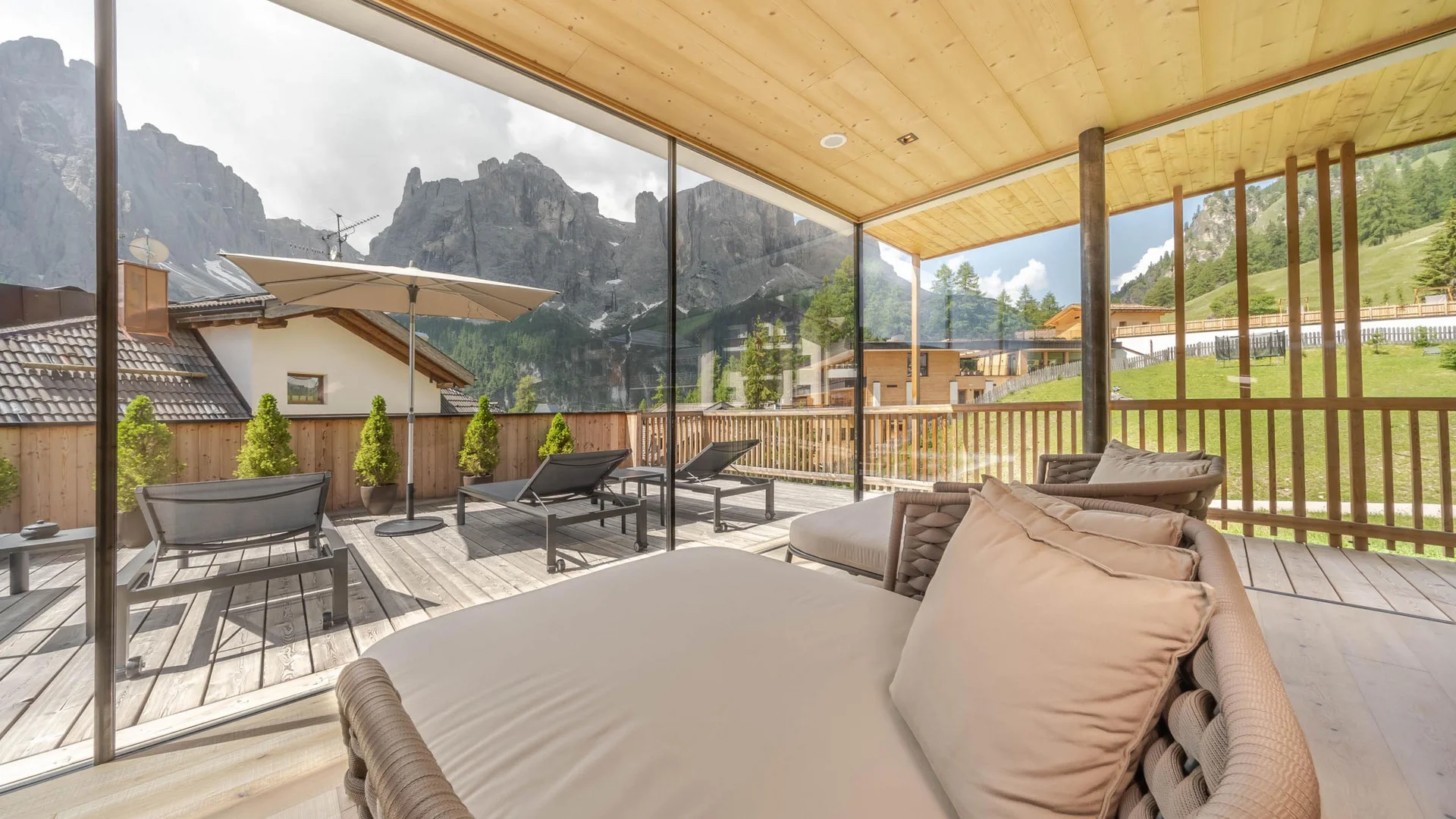 Terrasse mit Liegestühlen und Bergblick hinter Glaswand