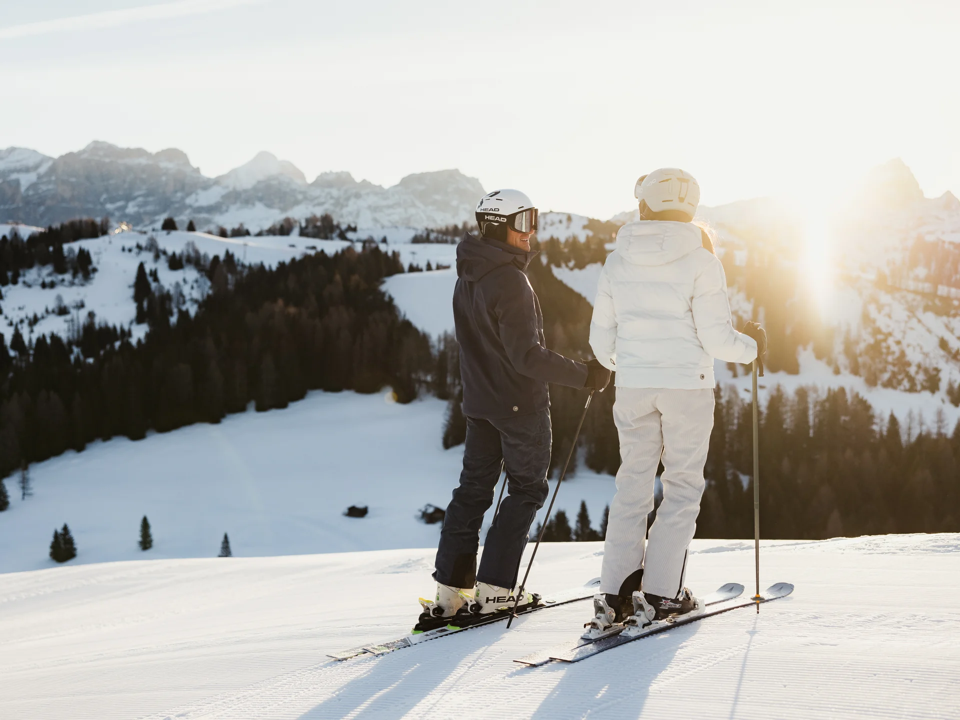 Zwei Skifahrer stehen auf schneebedecktem Berg mit Sonnenuntergang