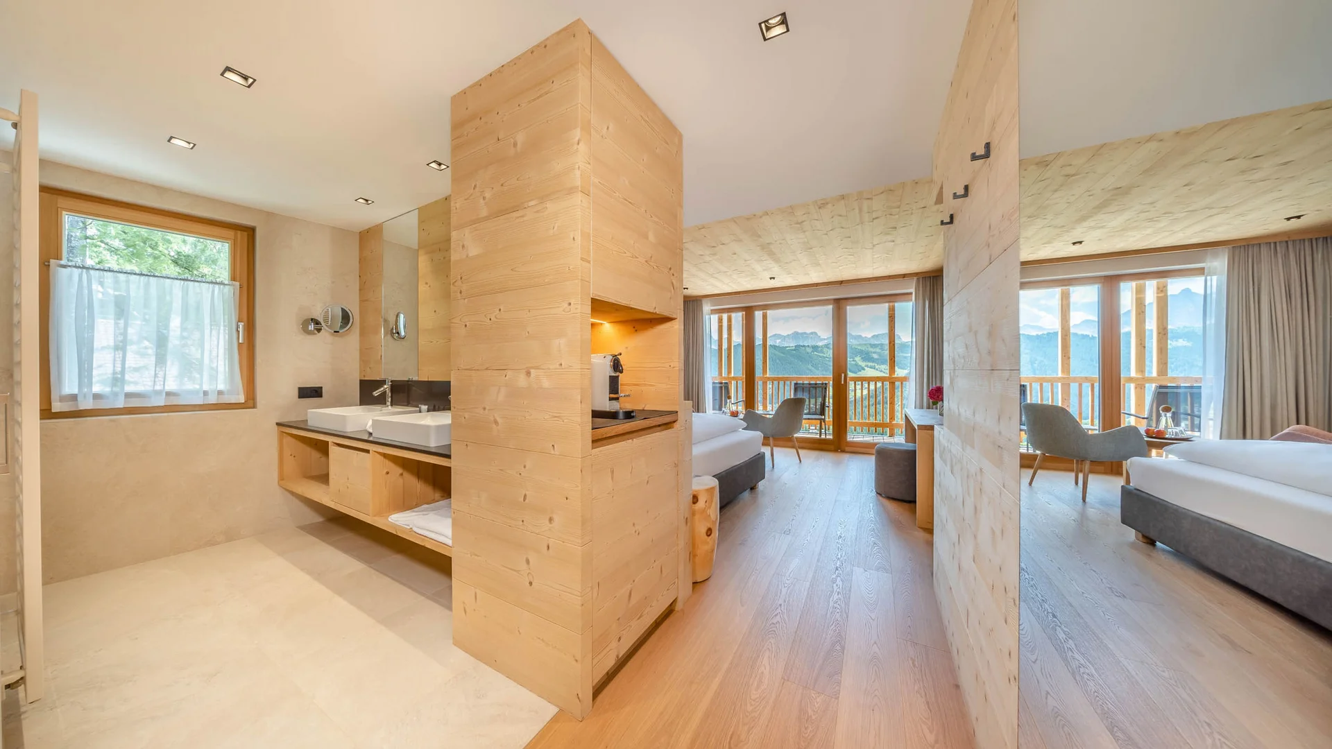 Die schönsten Eindrücke aus dem Nature Hotel Delta Modernes Hotelzimmer mit Holzakzenten und Bergblick durch große Fenster