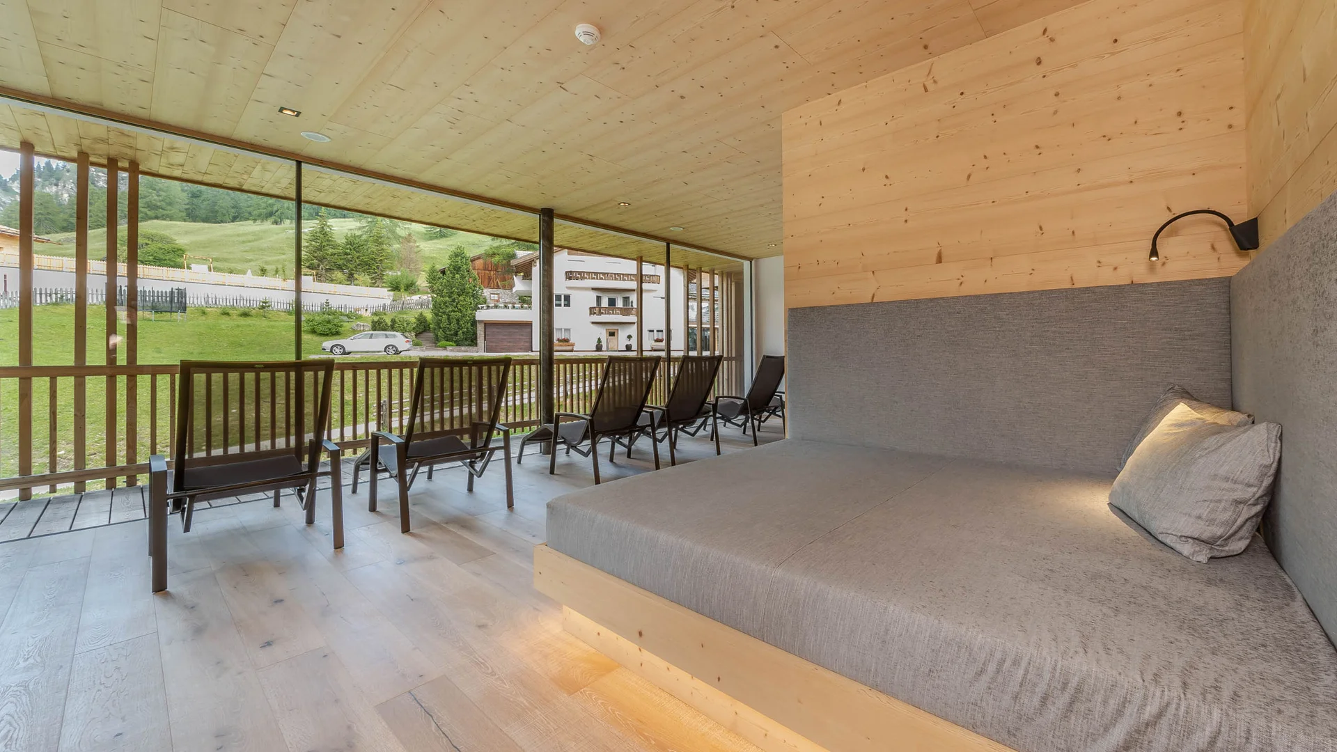 Die schönsten Eindrücke aus dem Nature Hotel Delta Moderner Ruheraum mit Liegen und Blick auf grüne Wiese und Gebäude