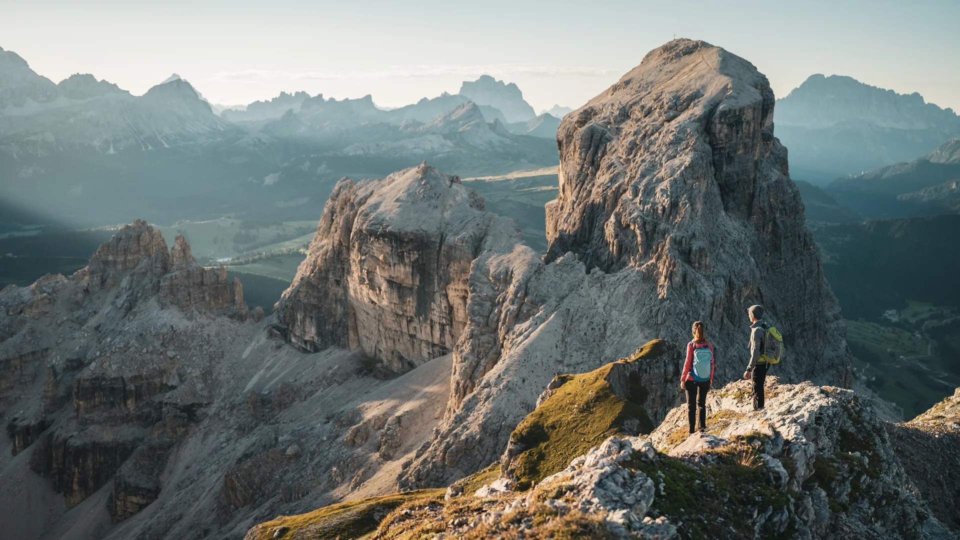 Zwei Wanderer auf felsigem Bergpfad mit Blick auf große Felsformationen
