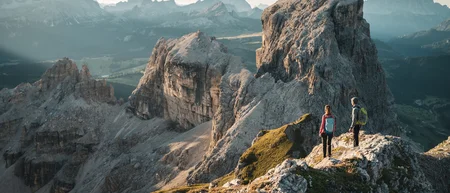 Zwei Wanderer auf felsigem Bergpfad mit Blick auf große Felsformationen