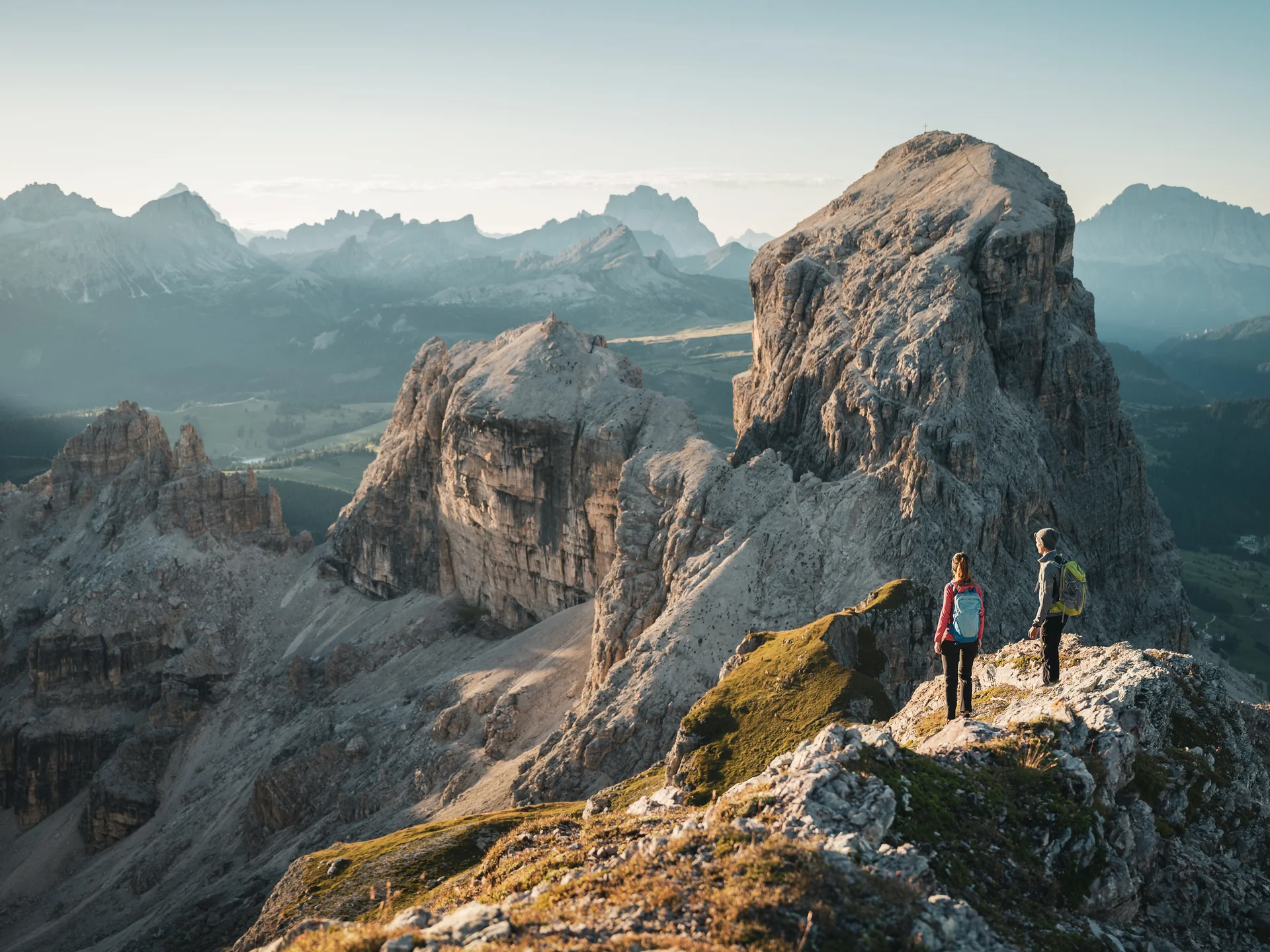 Auf zum Wandern in Alta Badia, rings ums Nature Hotel Delta! Zwei Wanderer auf felsigem Bergpfad mit Blick auf große Felsformationen