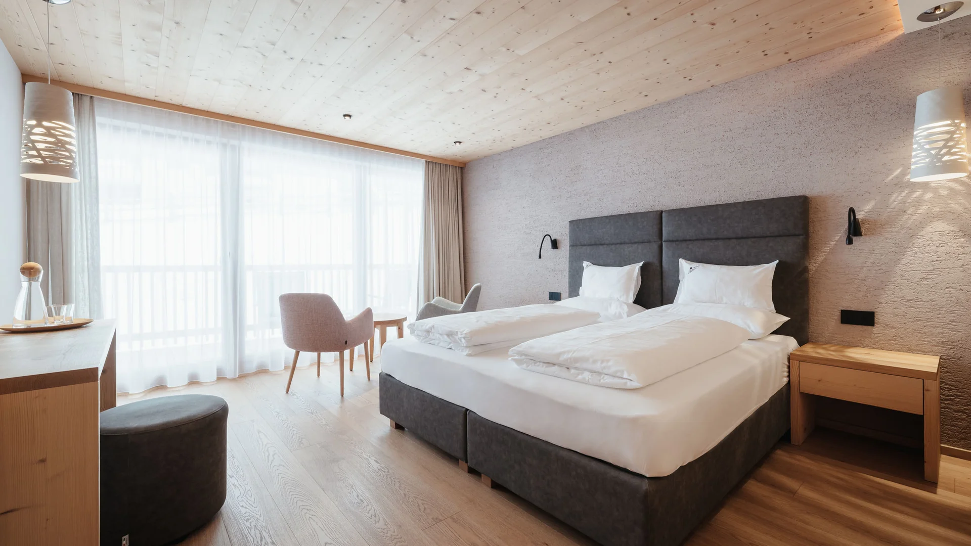 Die schönsten Eindrücke aus dem Nature Hotel Delta Modernes Hotelzimmer mit zwei Einzelbetten und Sitzbereich am Fenster