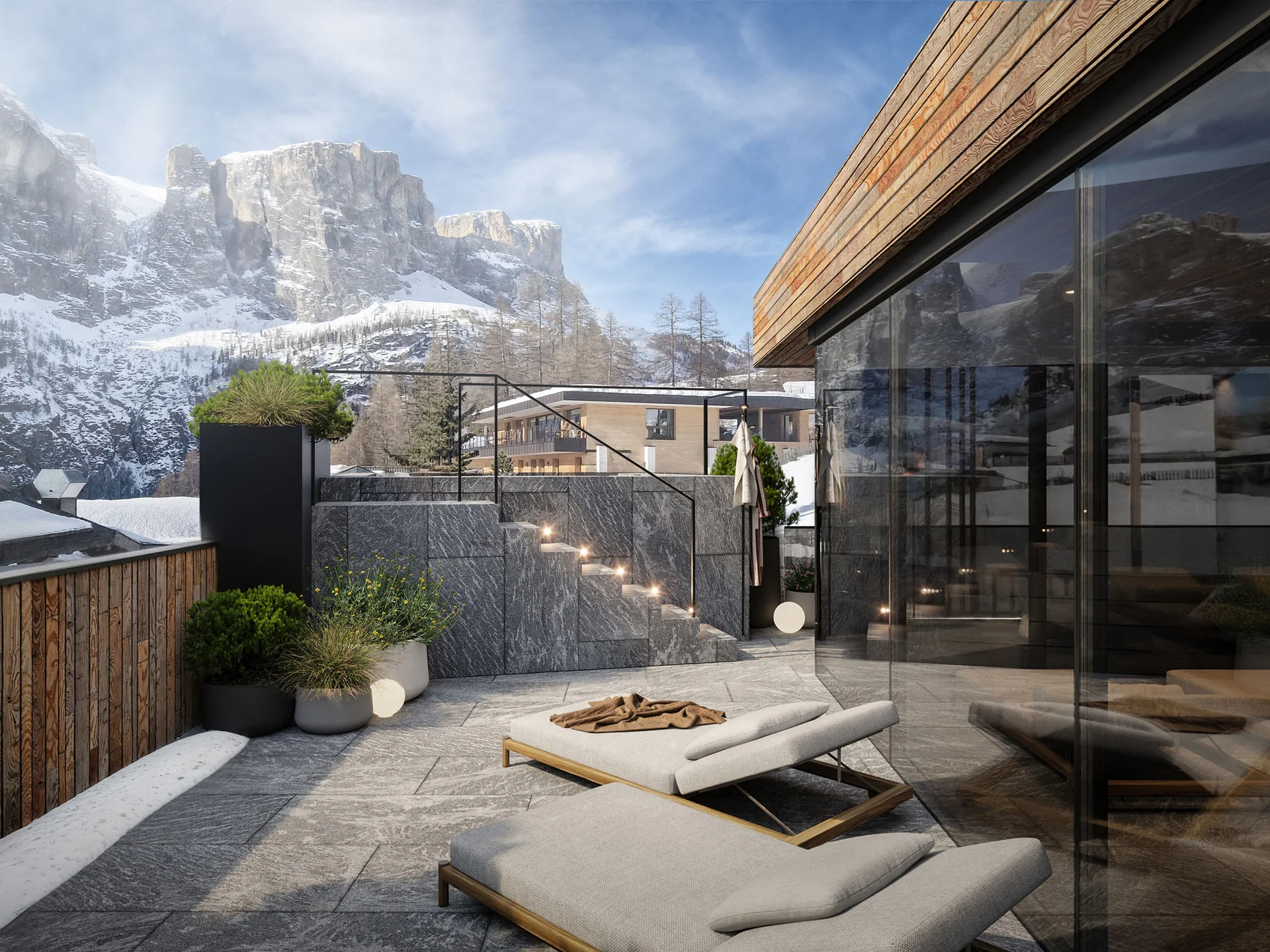 Unser Wellnesshotel in Alta Badia: das Nature Hotel Delta Terrasse mit Liegestühlen und Bergblick im Schnee bei klarem Himmel