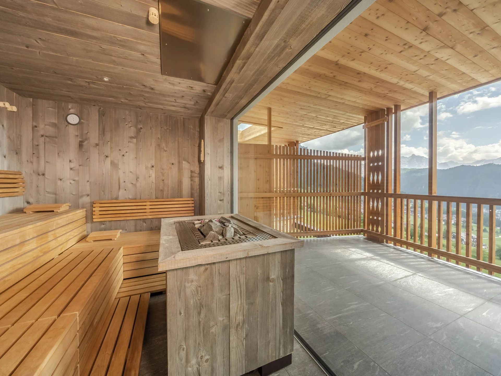 Unser Wellnesshotel in Alta Badia: das Nature Hotel Delta Sauna mit Holzinterieur und großer Glasfront mit Bergblick