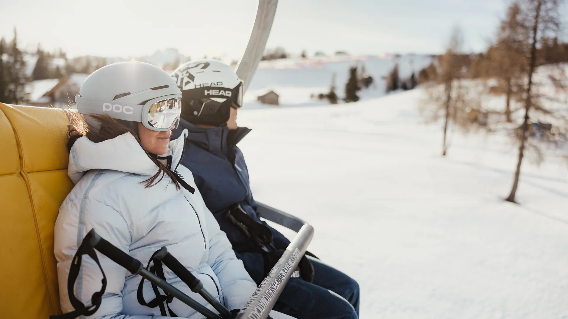 Die schönsten Eindrücke aus dem Nature Hotel Delta Zwei Skifahrer mit Helmen auf einem Skilift über verschneiter Landschaft
