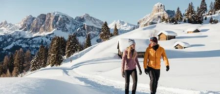 Paar wandert auf verschneitem Weg in den Bergen bei Sonnenschein