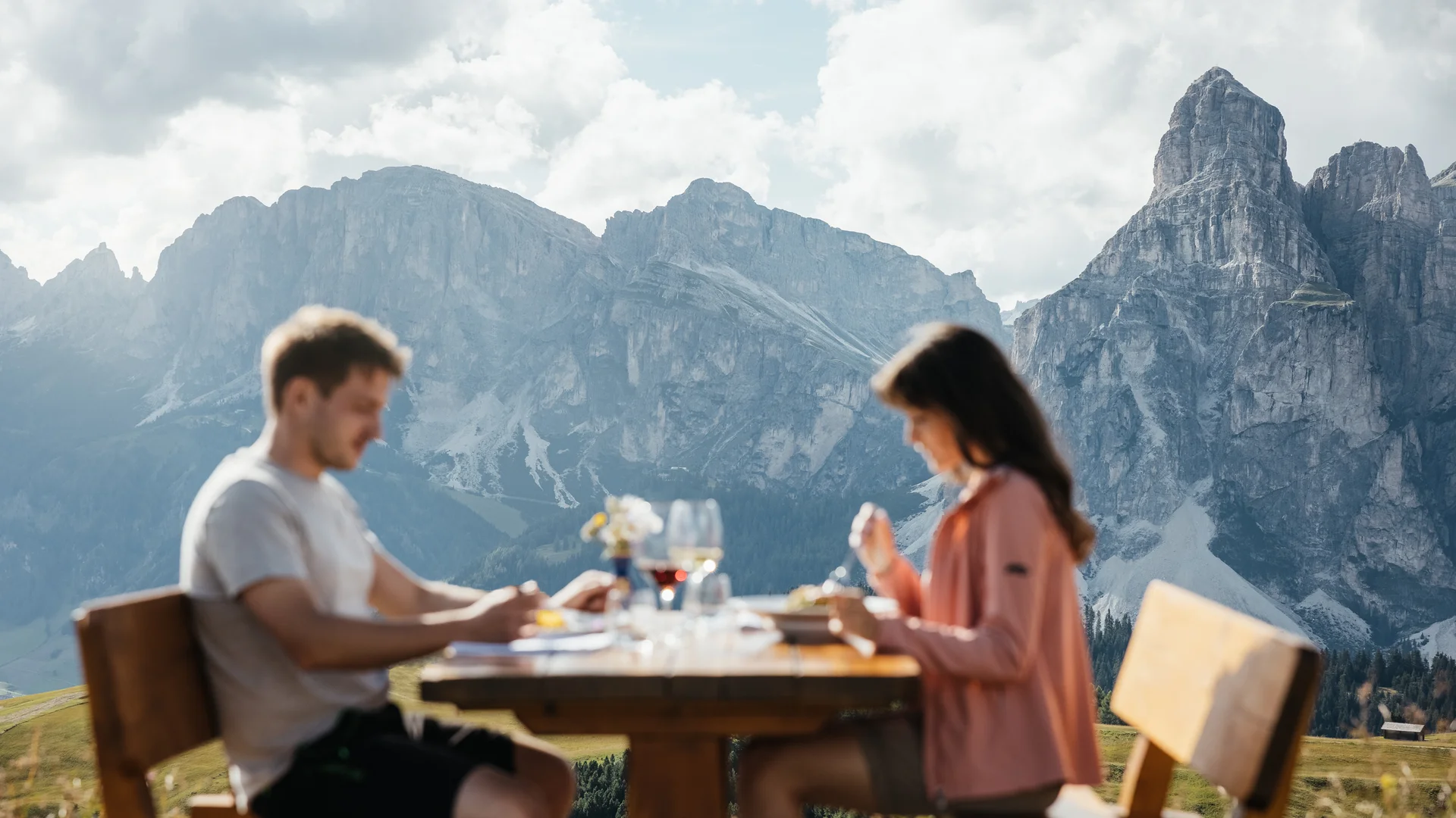 Die schönsten Eindrücke aus dem Nature Hotel Delta Paar isst draußen an Holztisch mit Bergpanorama im Hintergrund