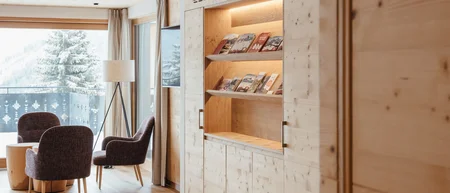 Gemütlicher Sitzbereich mit Stühlen, Tisch und Bücherregal in hellem Holz