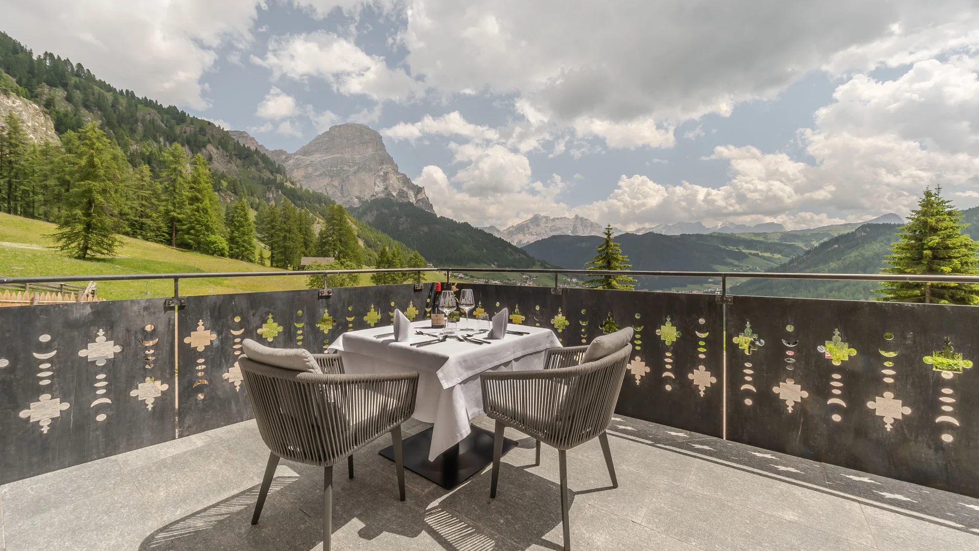Die schönsten Eindrücke aus dem Nature Hotel Delta Esstisch mit zwei Stühlen auf Balkon mit Bergblick und bewölktem Himmel