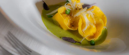 Gelbe Tortellini auf grünem Erbsenpüree mit Käse und Kräutern