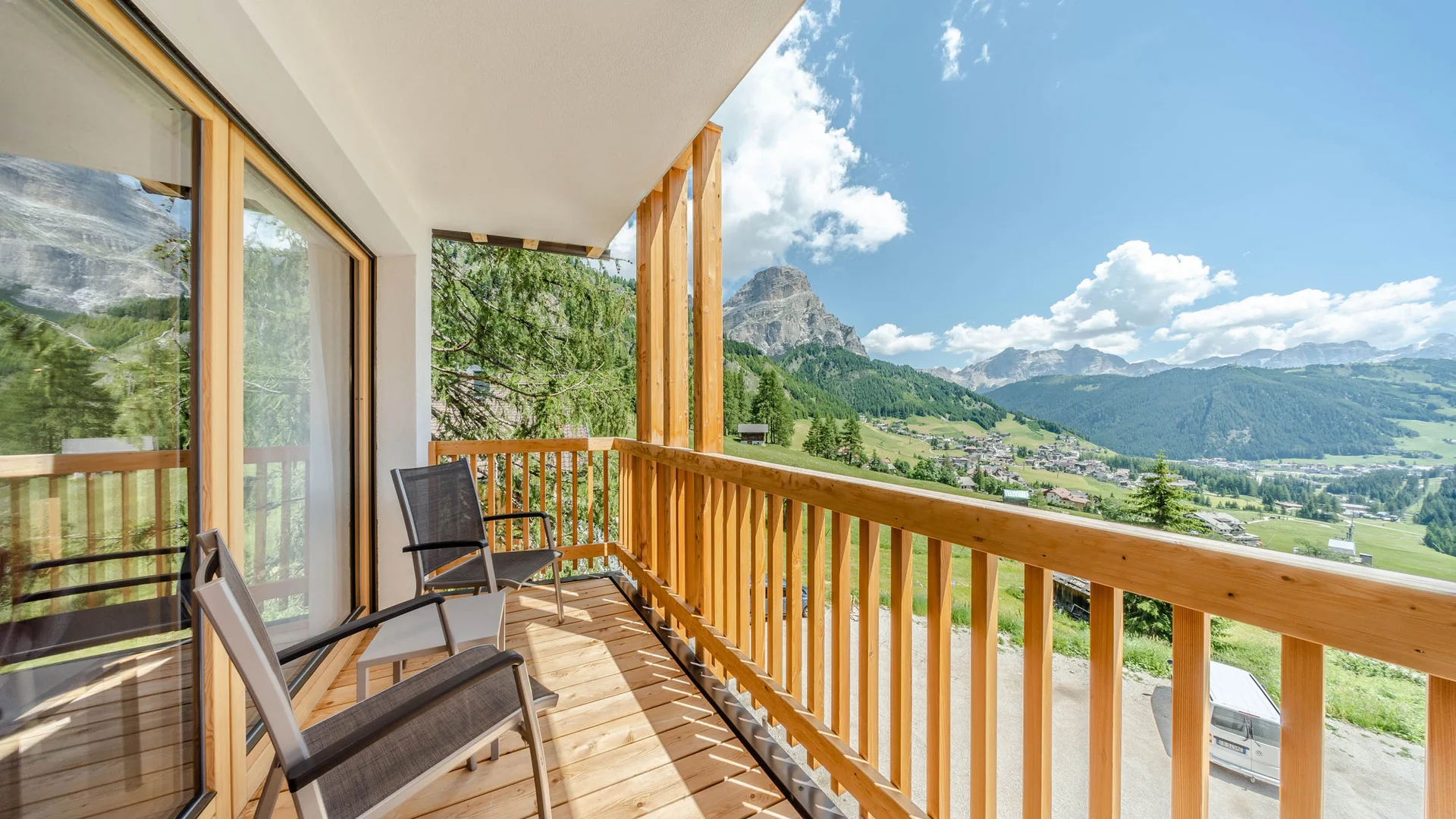 Die schönsten Eindrücke aus dem Nature Hotel Delta Balkon mit Stühlen und Blick auf Berge und Tal bei klarem Himmel