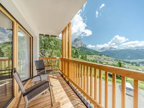 Balkon mit Stühlen und Blick auf Berge und Tal bei klarem Himmel