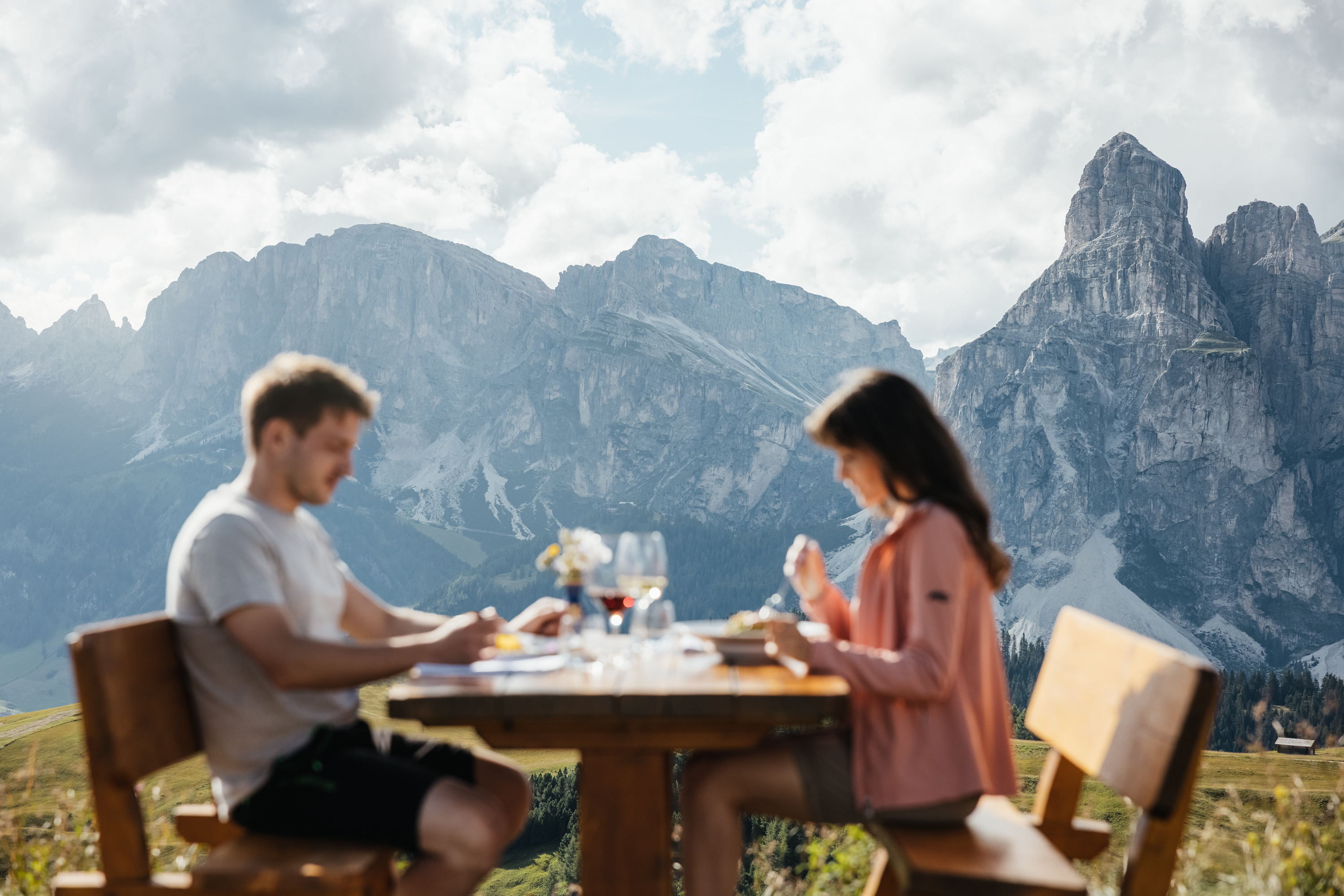 Das ist sehenswert in der Umgebung des Nature Hotel Delta. Paar isst draußen an Holztisch mit Bergpanorama im Hintergrund