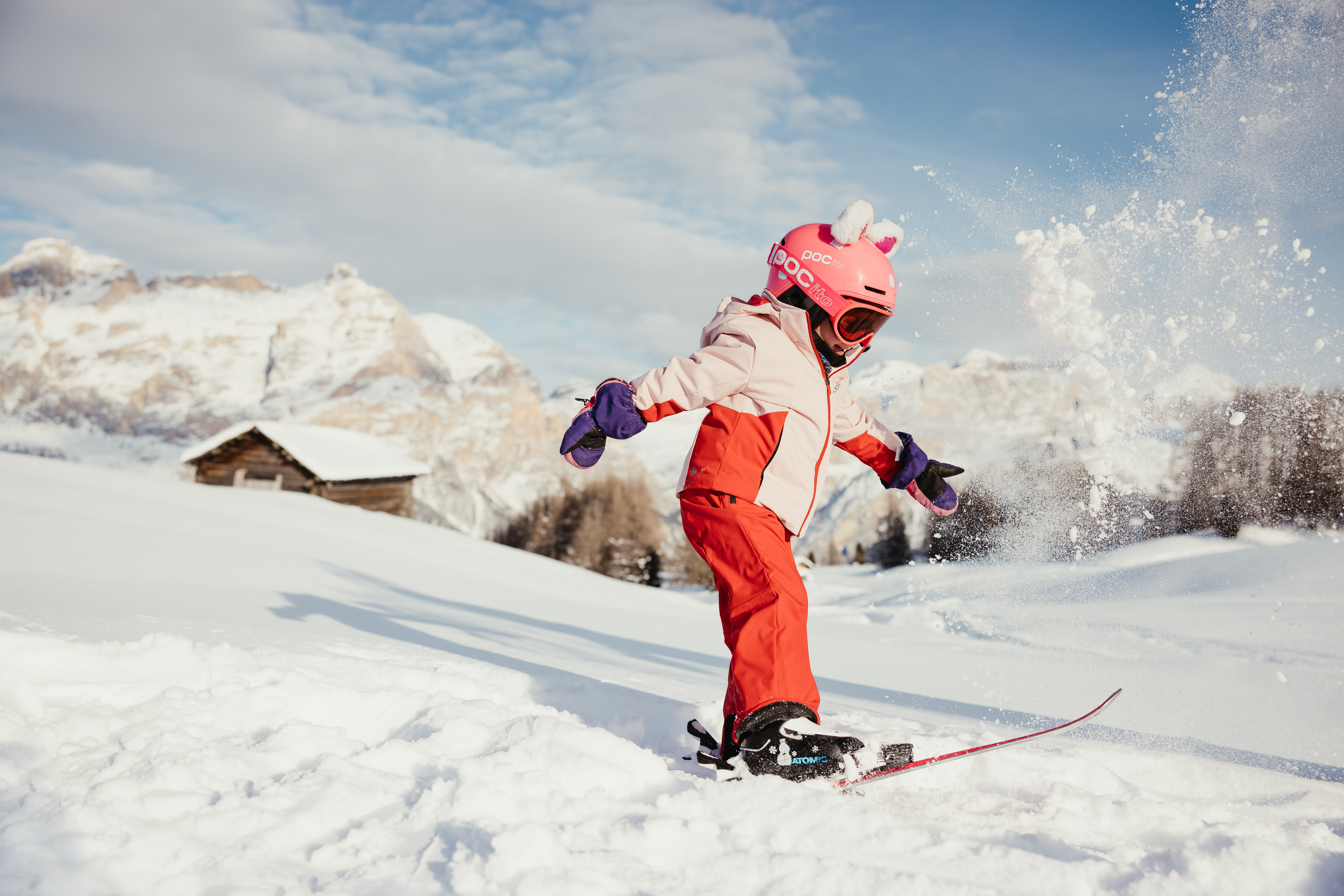 Bambino con abbigliamento da sci rosso scia sulla neve in montagna