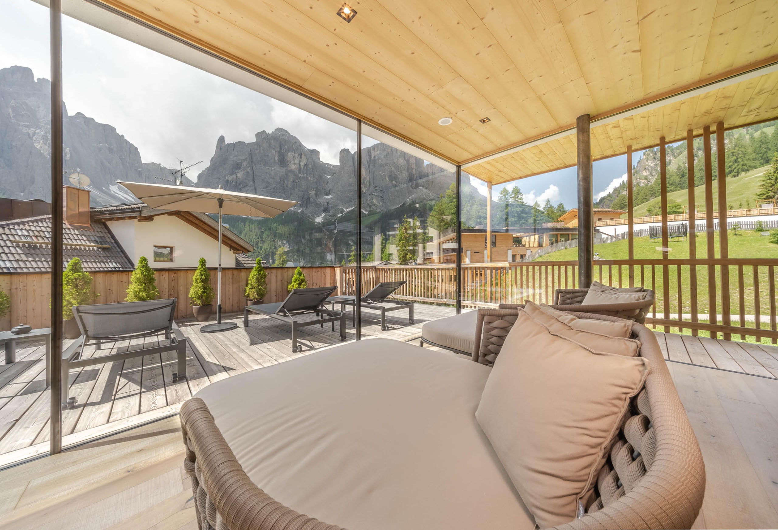 Il vostro hotel con spa in Alta Badia: il Nature Hotel Delta Terrazza con lettini prendisole e vista sulle montagne oltre la vetrata
