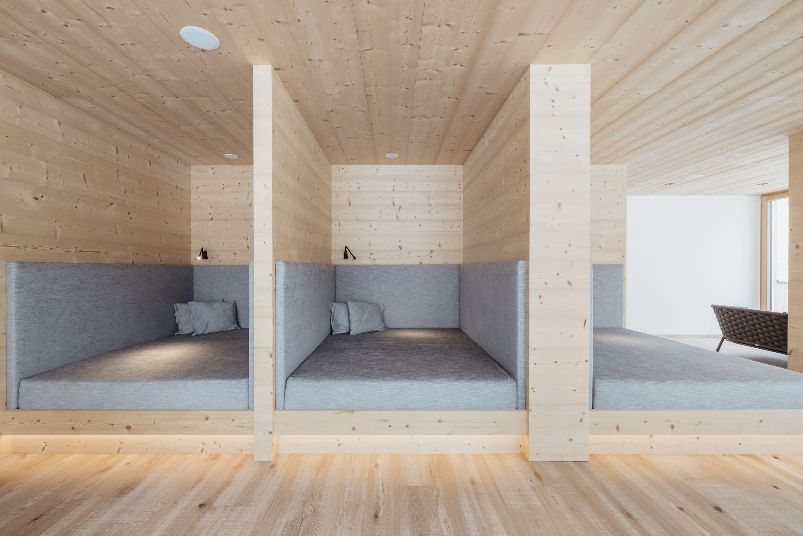 Unser Wellnesshotel in Alta Badia: das Nature Hotel Delta Moderne Holznischen mit grauen Polstern und Kissen in einem hellen Raum